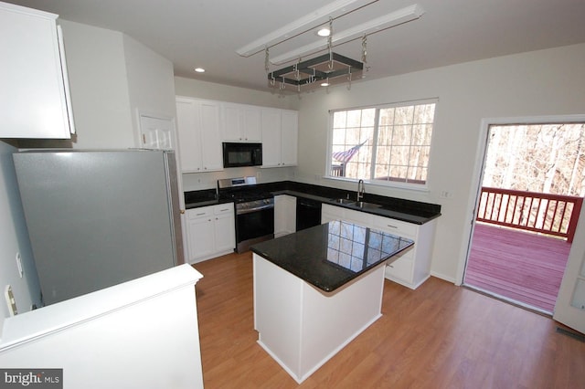 kitchen with black appliances, light wood-style flooring, white cabinetry, and a sink