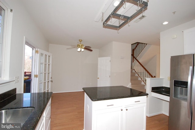 kitchen with ceiling fan, white cabinets, stainless steel refrigerator with ice dispenser, light wood finished floors, and dark stone countertops