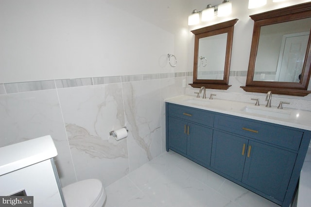 bathroom with marble finish floor, a sink, tile walls, and toilet