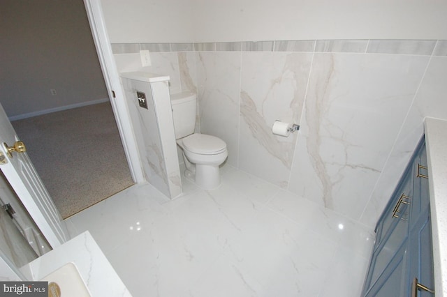 bathroom with vanity, toilet, and tile walls