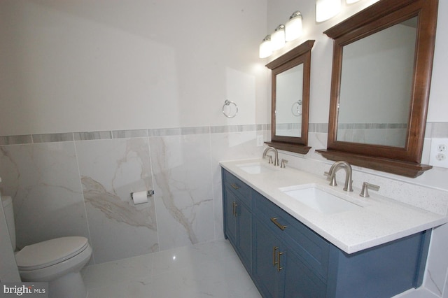 bathroom featuring a sink, tile walls, toilet, and double vanity