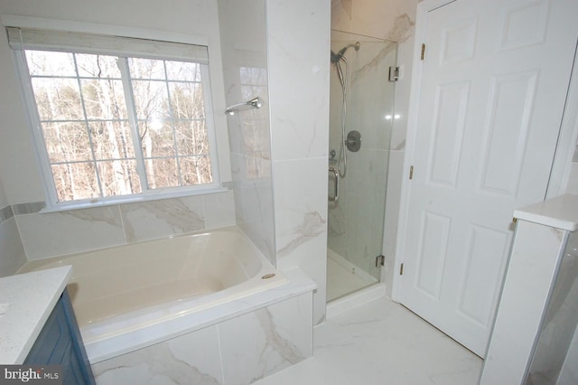 bathroom featuring marble finish floor, vanity, a garden tub, and a stall shower