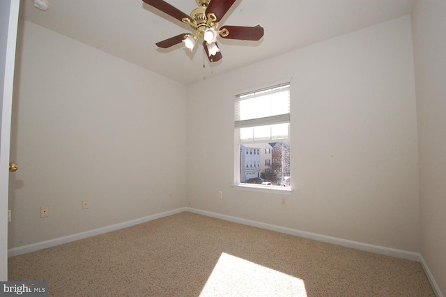 spare room with a ceiling fan and baseboards