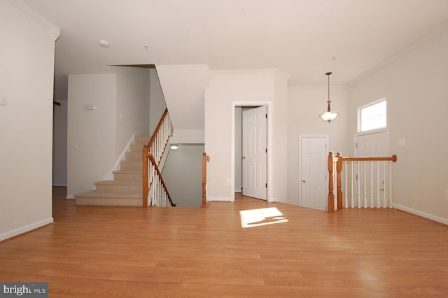 unfurnished living room featuring baseboards, ornamental molding, and wood finished floors