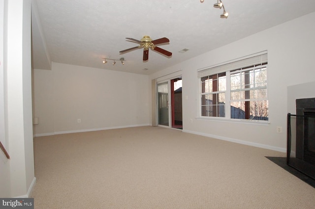 unfurnished living room featuring carpet flooring, a fireplace with flush hearth, visible vents, and baseboards