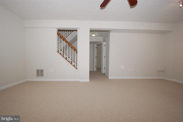 spare room featuring baseboards, visible vents, a ceiling fan, light colored carpet, and stairway