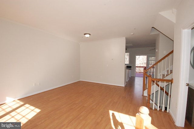 spare room with stairs, baseboards, and wood finished floors