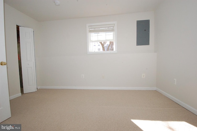 carpeted spare room featuring electric panel and baseboards