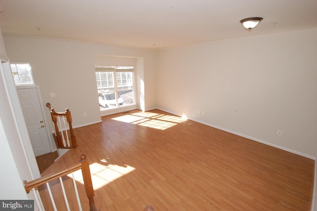 empty room featuring light wood-style flooring, a wealth of natural light, and baseboards