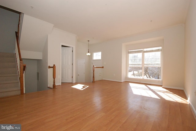 unfurnished living room with stairway, baseboards, ornamental molding, and wood finished floors