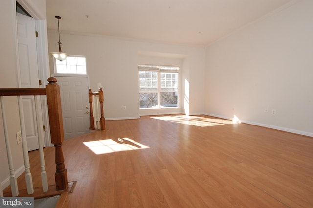 unfurnished living room featuring ornamental molding, baseboards, and wood finished floors