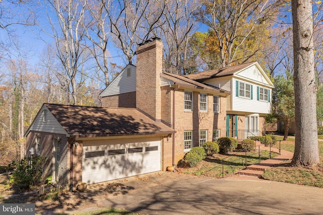 split level home with an attached garage, brick siding, a shingled roof, driveway, and a chimney