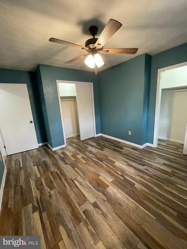 unfurnished bedroom with ceiling fan, baseboards, dark wood finished floors, and a textured ceiling