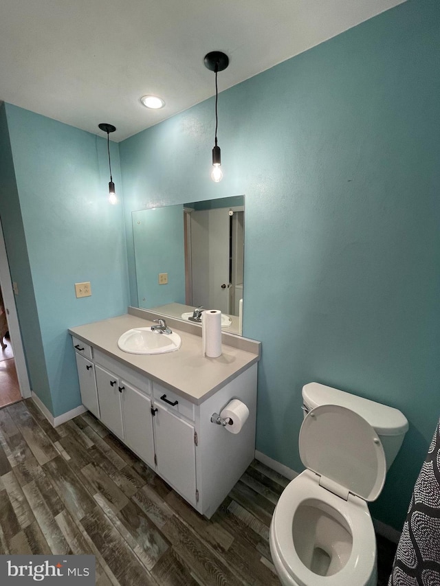 bathroom featuring vanity, wood finished floors, toilet, and baseboards