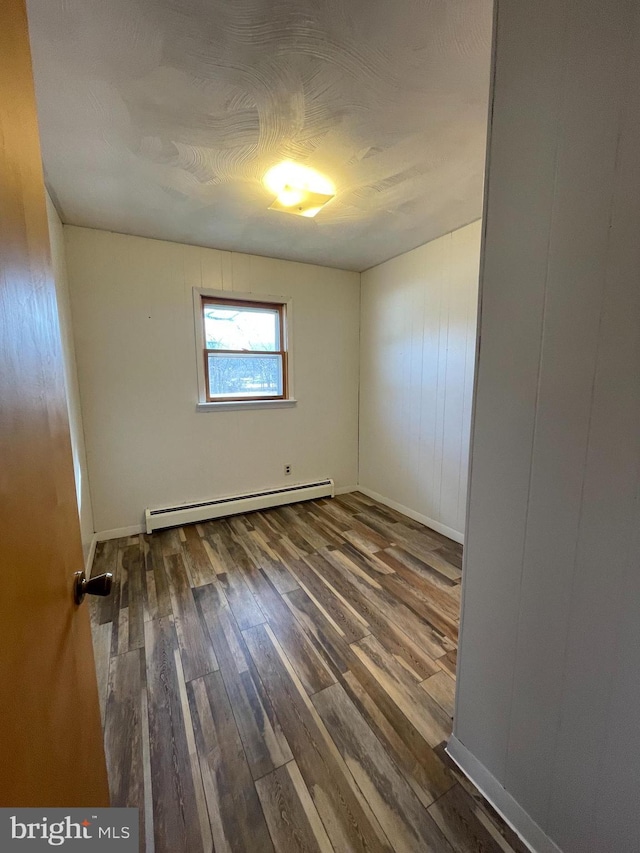 spare room featuring a baseboard radiator and wood finished floors