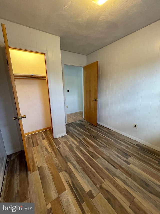 unfurnished bedroom featuring a closet, baseboards, and dark wood-type flooring