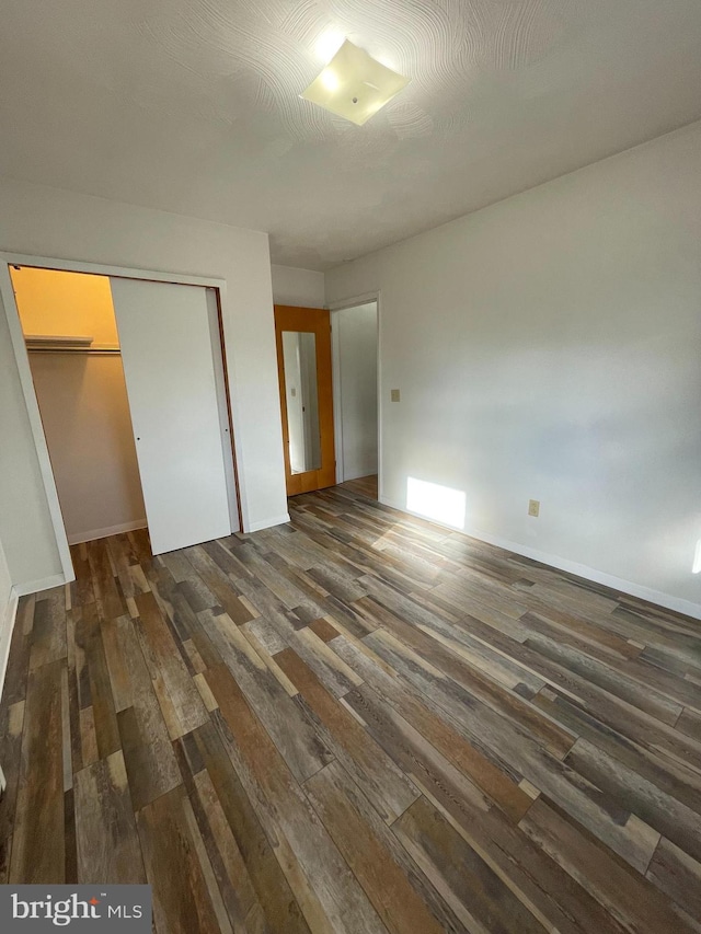 unfurnished bedroom featuring dark wood-type flooring and a closet