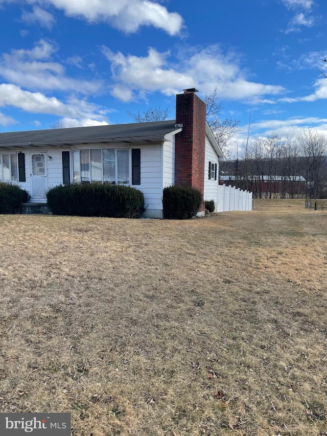 view of front of home with a front yard, fence, and a chimney