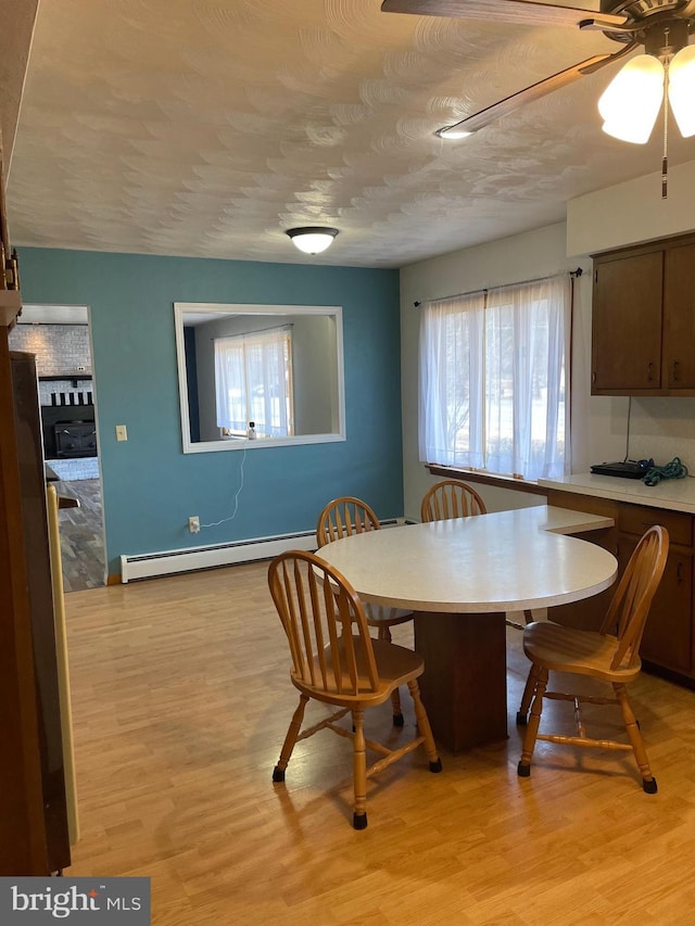 dining space with a baseboard radiator, light wood-style flooring, and a textured ceiling