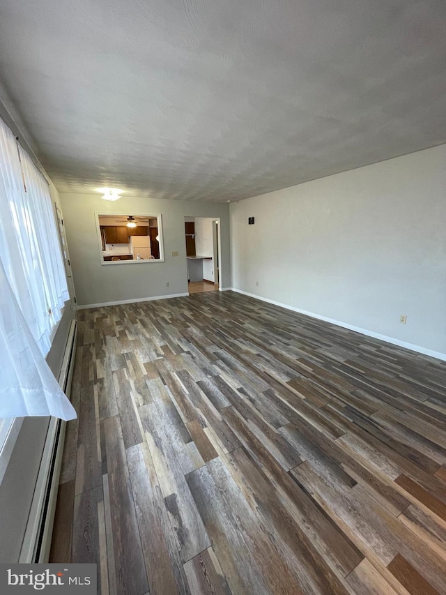 unfurnished living room with a baseboard radiator, dark wood finished floors, and baseboards