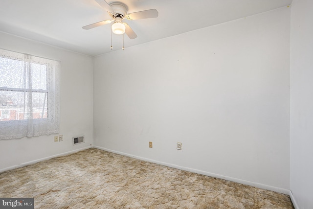 carpeted spare room with ceiling fan, visible vents, and baseboards