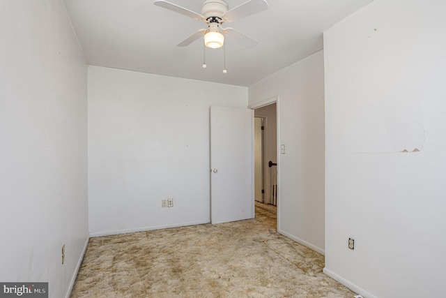 spare room with a ceiling fan and baseboards