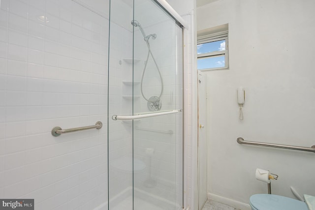 bathroom featuring toilet, a stall shower, and baseboards