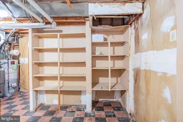 unfinished basement with water heater and tile patterned floors