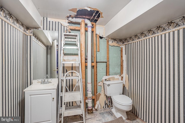 bathroom featuring concrete block wall, vanity, and toilet