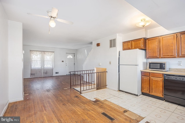 kitchen with black dishwasher, visible vents, stainless steel microwave, and freestanding refrigerator