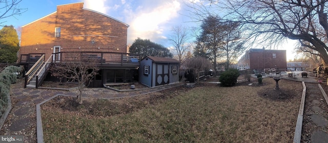 view of yard with a shed, stairway, a wooden deck, and an outbuilding