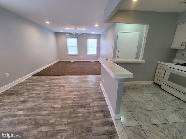 kitchen featuring white gas stove, light countertops, a ceiling fan, white cabinets, and baseboards