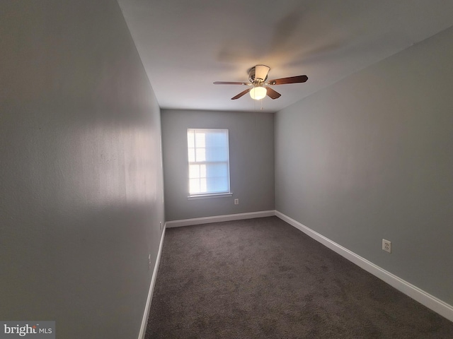 empty room featuring ceiling fan, dark carpet, and baseboards