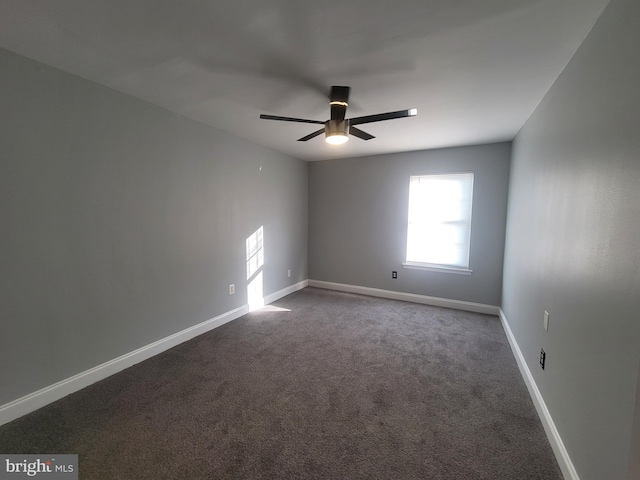 empty room with ceiling fan, baseboards, and dark carpet