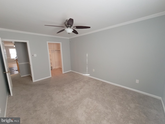 unfurnished bedroom with a walk in closet, crown molding, and carpet