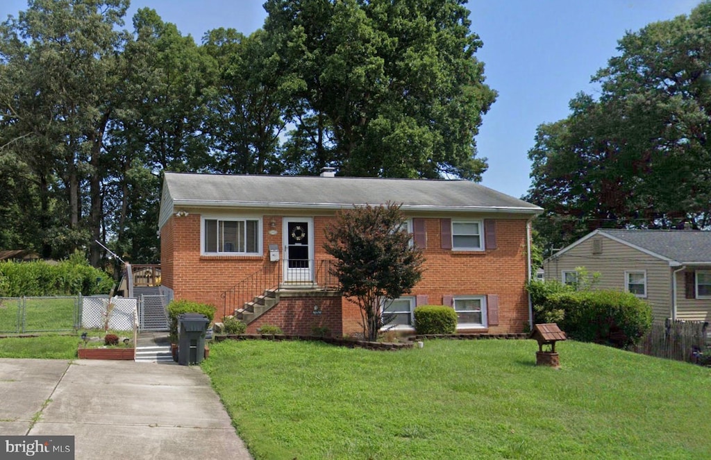 view of front of property with brick siding, a front lawn, fence, and a gate