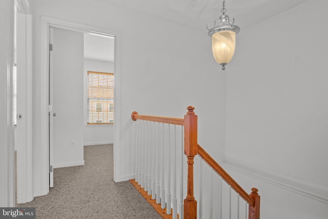 hallway featuring carpet flooring, baseboards, and an upstairs landing