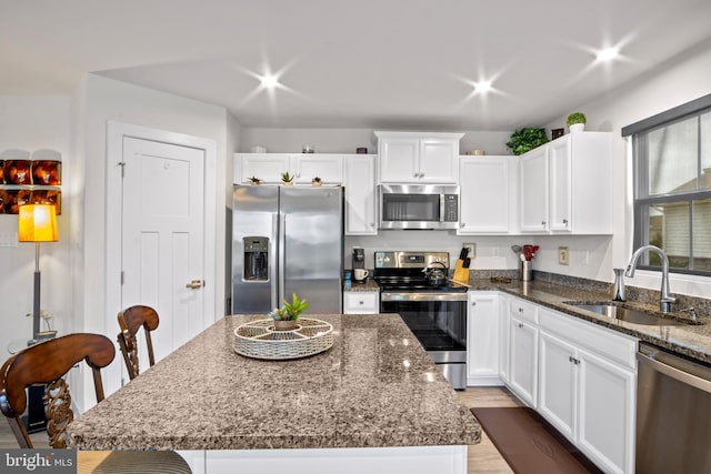 321 Windflower Dr Unit 9, Millsboro, DE 19966 - kitchen with a center island, appliances with stainless steel finishes, white cabinetry, a sink, and dark stone counters