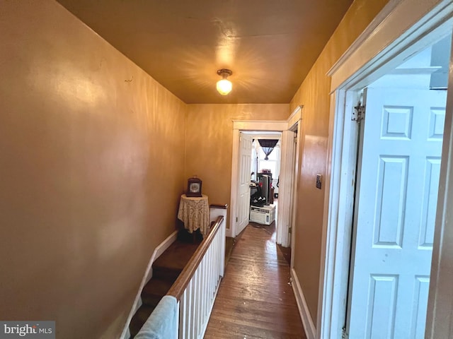 hallway featuring dark wood finished floors and baseboards