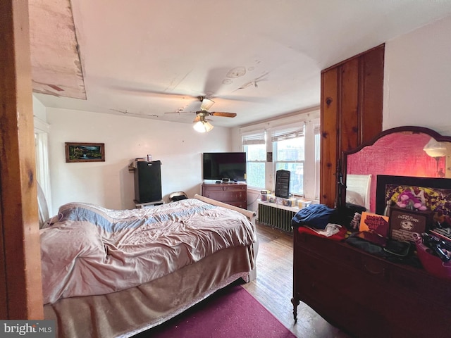 bedroom featuring radiator heating unit, a ceiling fan, and wood finished floors