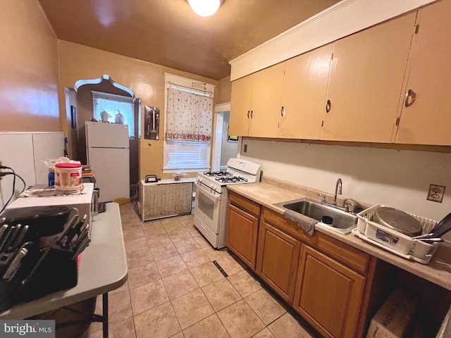 kitchen featuring light tile patterned floors, light countertops, brown cabinetry, a sink, and white appliances