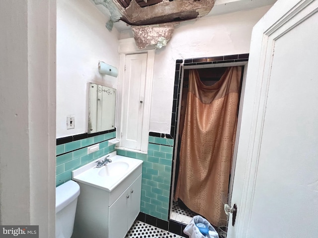 full bath featuring tile walls, toilet, a stall shower, wainscoting, and vanity