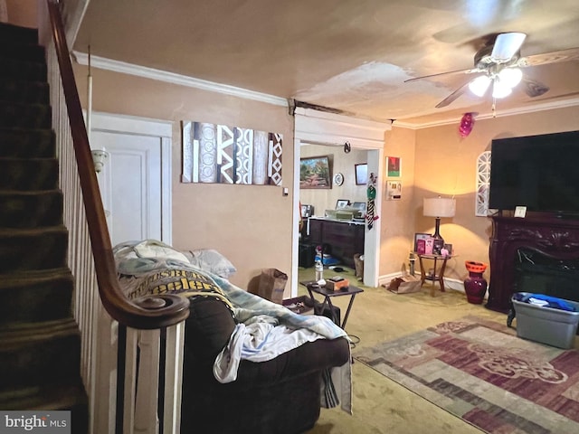 carpeted living room featuring a ceiling fan, crown molding, baseboards, and stairs