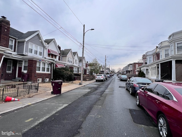 view of street with a residential view, curbs, sidewalks, and street lights