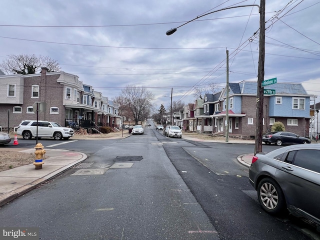 view of street featuring a residential view, curbs, sidewalks, and street lights