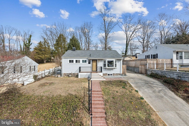 view of front of house with a chimney, a front yard, and fence