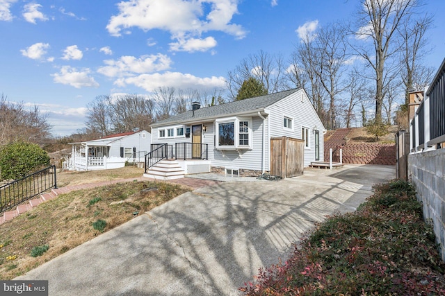 bungalow-style home featuring driveway, roof with shingles, and fence