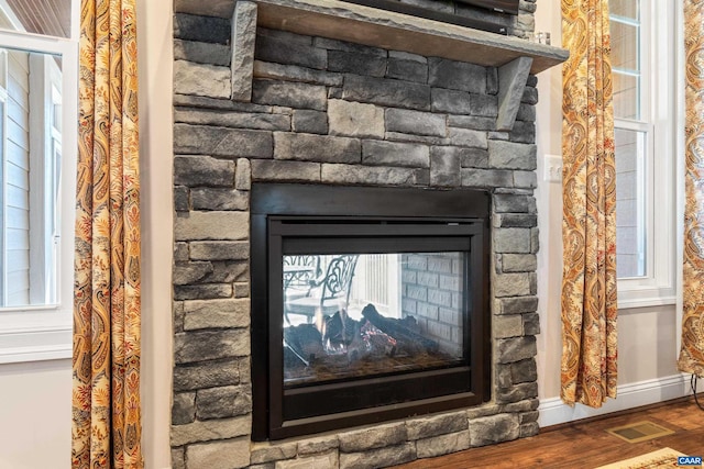 details featuring baseboards, a fireplace, visible vents, and wood finished floors