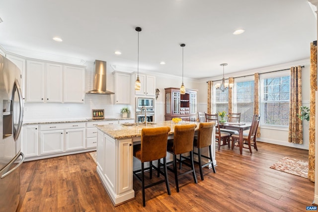 kitchen with appliances with stainless steel finishes, dark wood-type flooring, wall chimney range hood, and white cabinetry