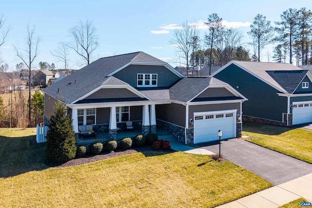 craftsman-style home featuring concrete driveway, stone siding, an attached garage, covered porch, and a front lawn